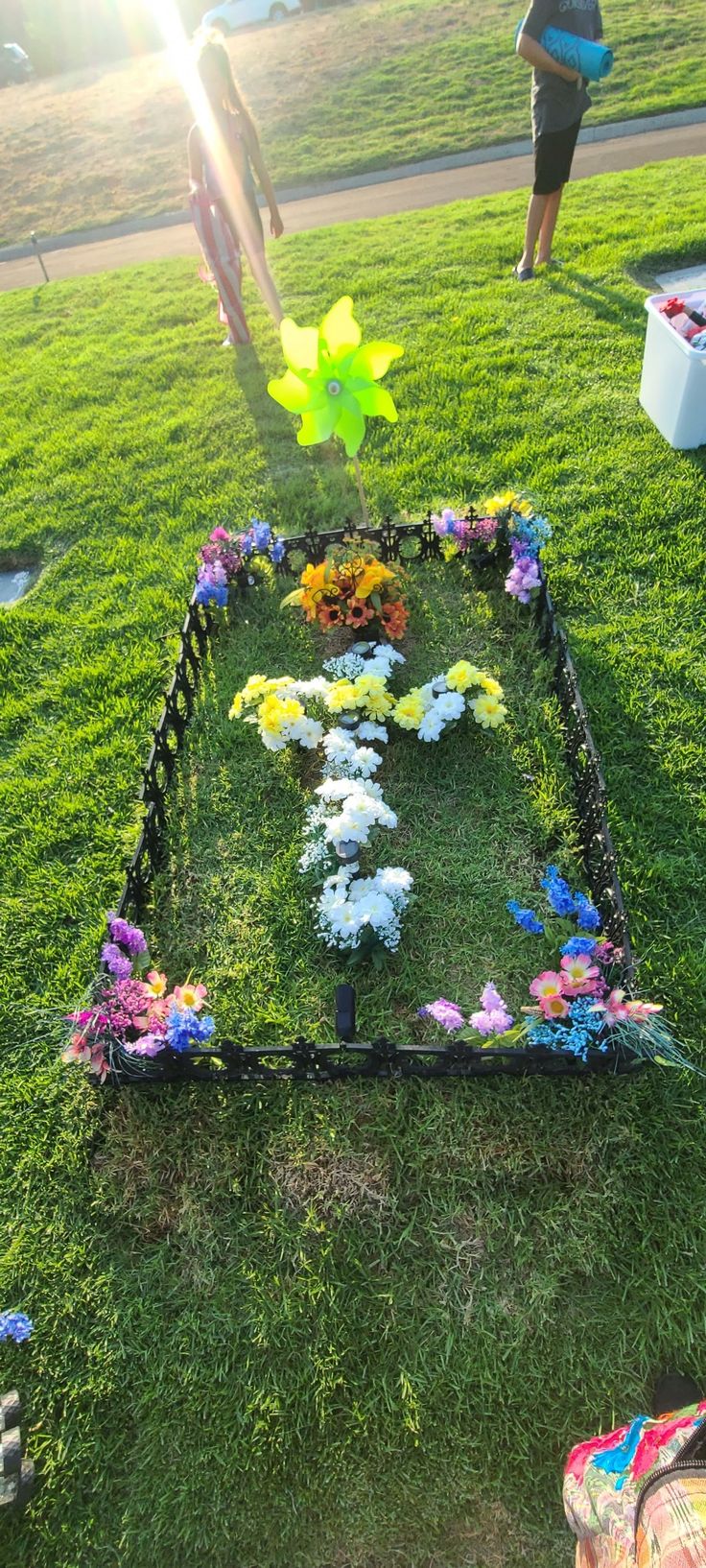 two people standing in the grass near a flower garden with flowers and stars on it