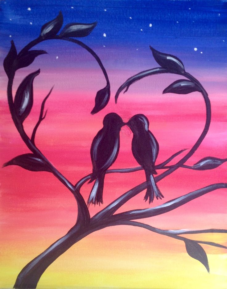 two birds sitting on a tree branch in front of a colorful sky