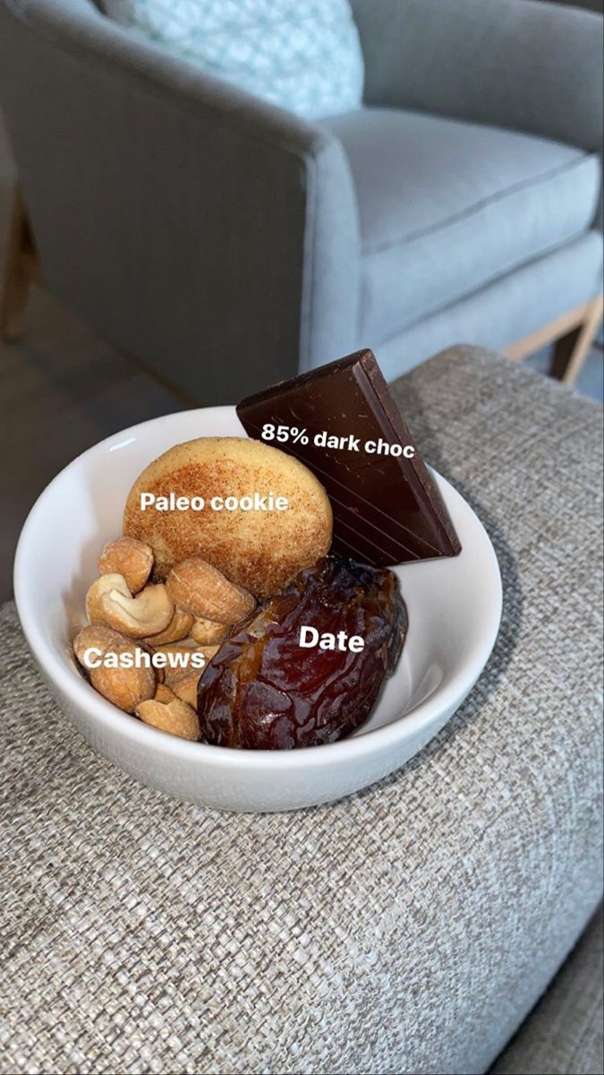 a white bowl filled with assorted desserts on top of a table next to a gray chair