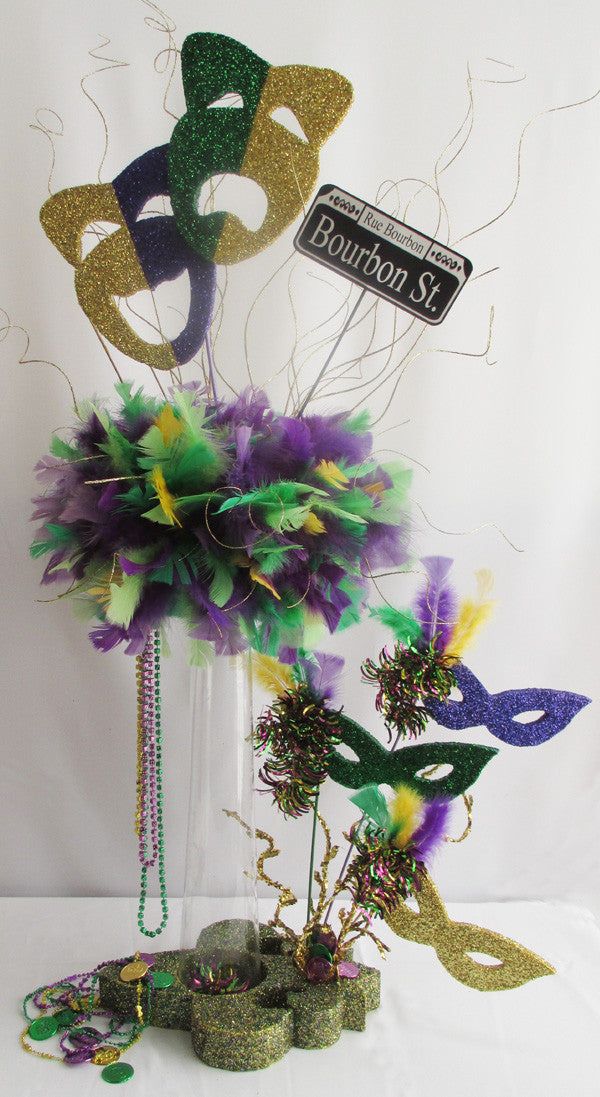 mardi gras decorations and masks are on display in a clear vase with streamers