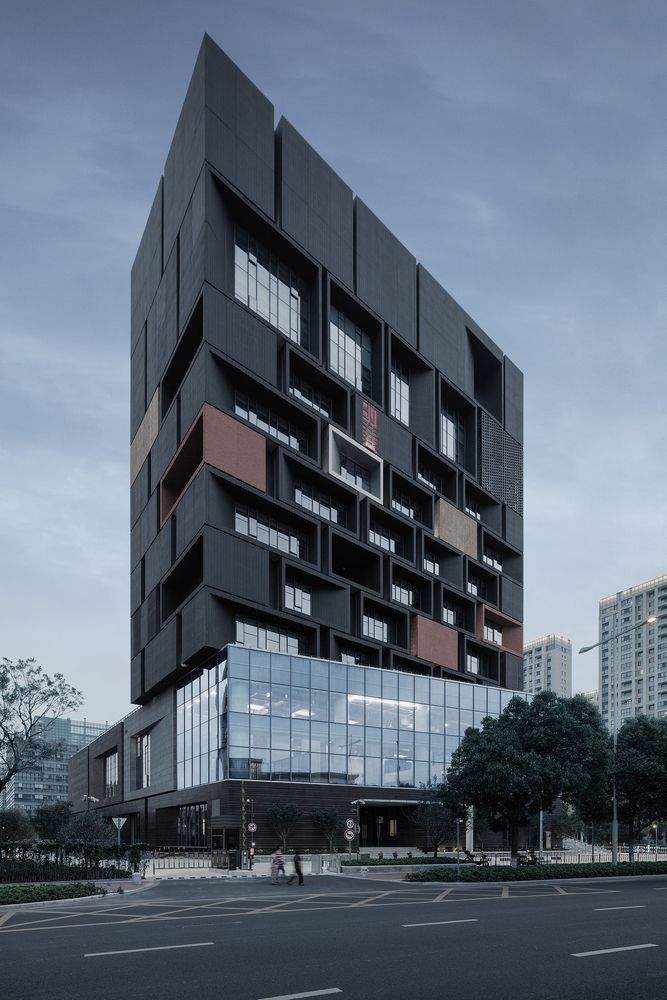 a tall building with lots of windows on top of it's sides in the middle of a street