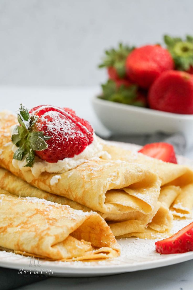 crepes with powdered sugar and strawberries on the side are ready to be eaten