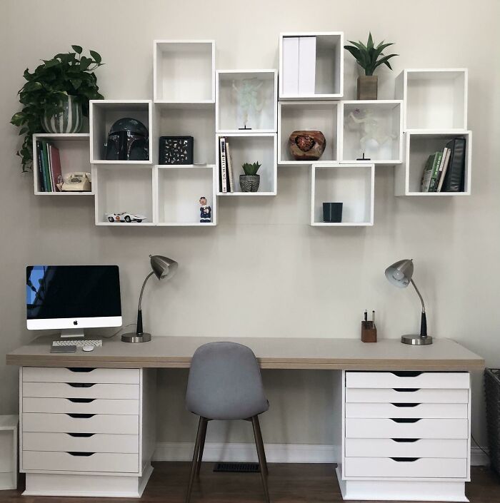 an office desk with white shelving units on the wall