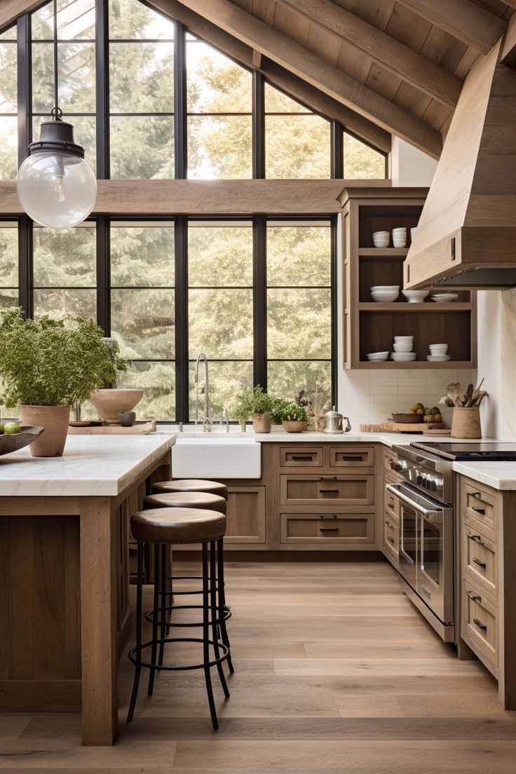 a kitchen with wooden floors and lots of counter space in the center, surrounded by large windows