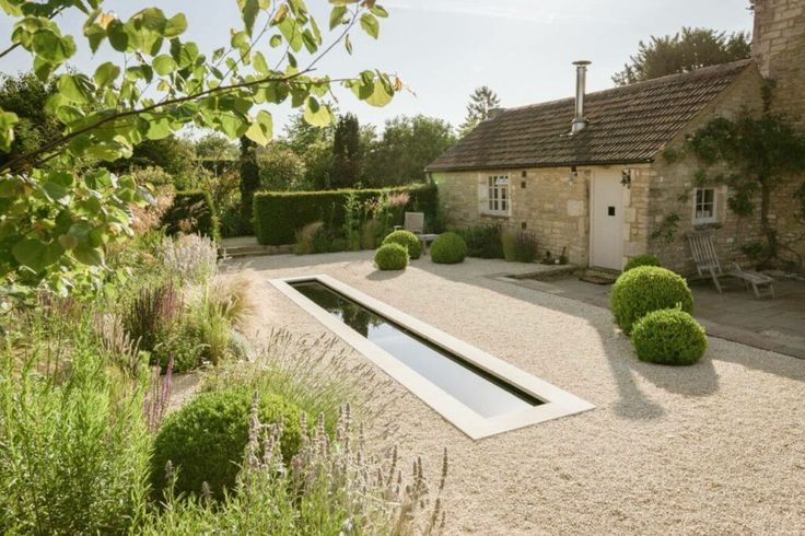 a house with a pool in the middle of it and lots of bushes around it