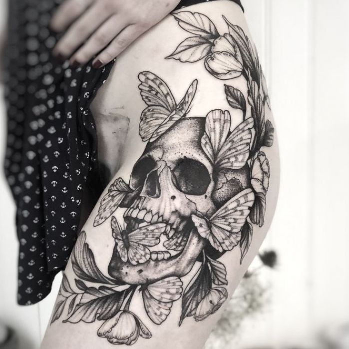 a woman's thigh with a skull and flowers on it