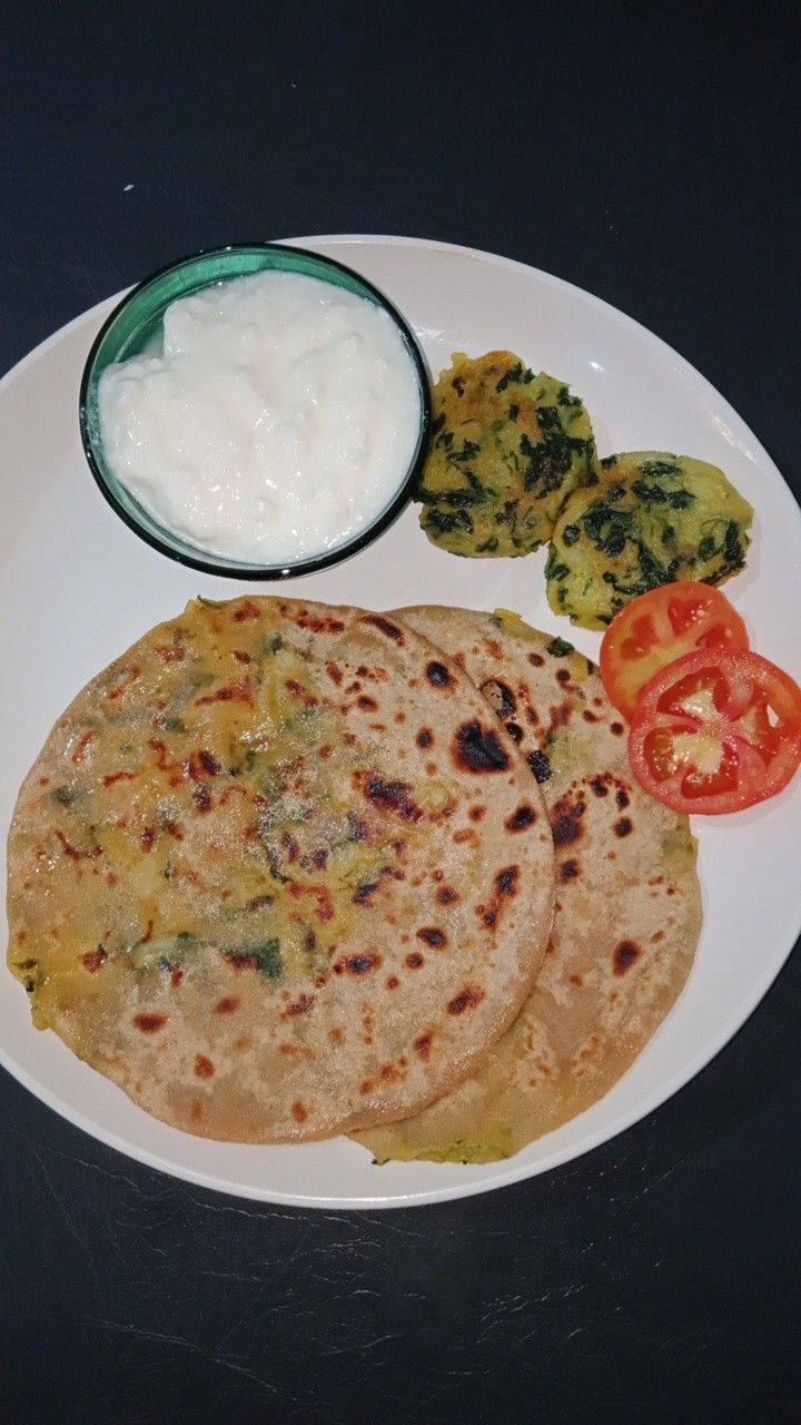 two flatbreads on a white plate with vegetables and yogurt