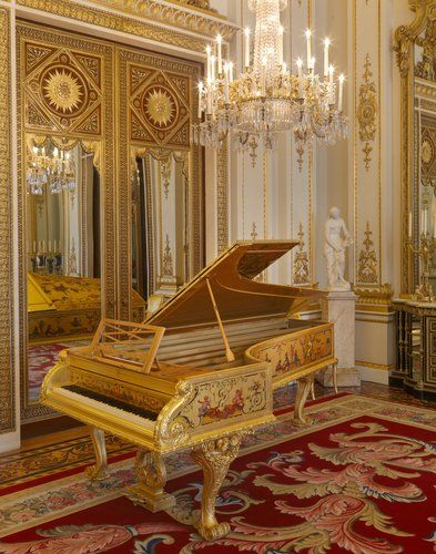 a grand piano sitting in the middle of a room with chandelier and mirror