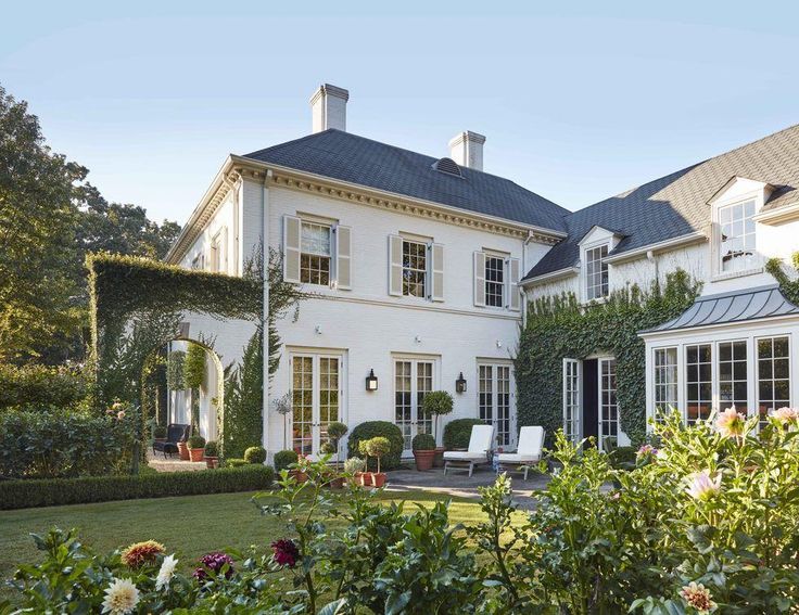 a large white house surrounded by greenery and flowers