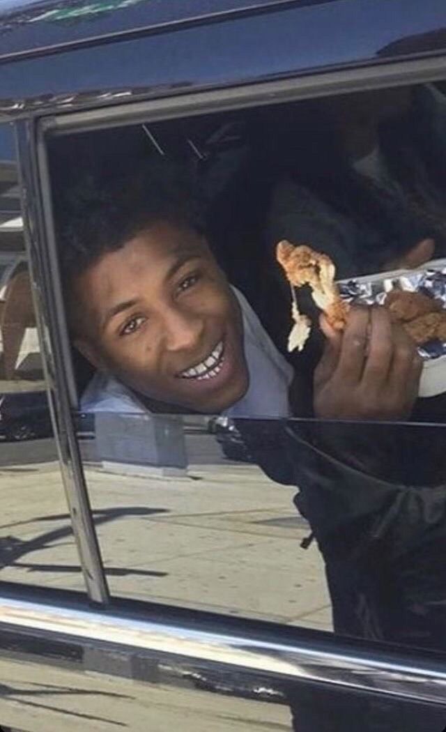 a man is smiling and holding food in his hand while sitting in the back of a car