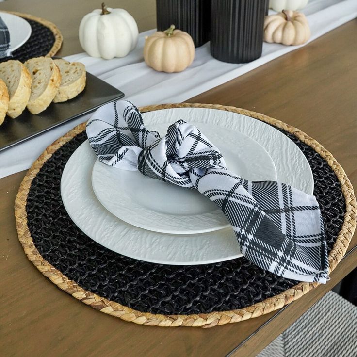 the table is set with black and white plates, napkins, and pumpkins