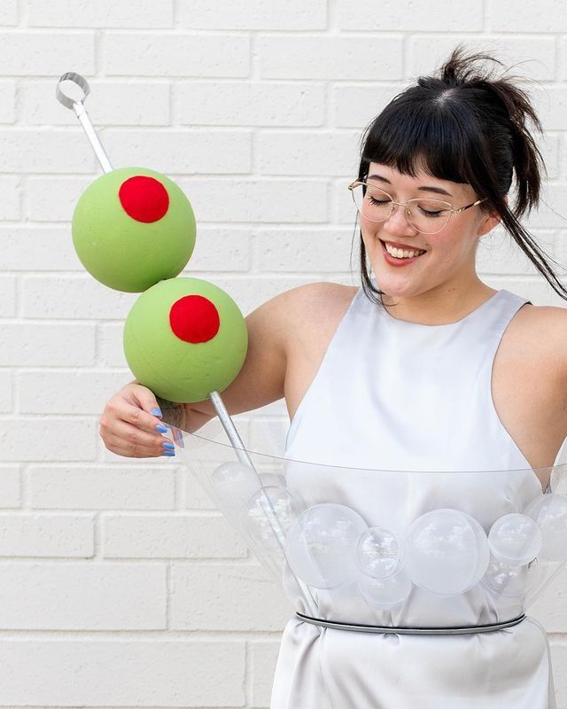 a woman in white dress holding two green balls with red polka dots on them,