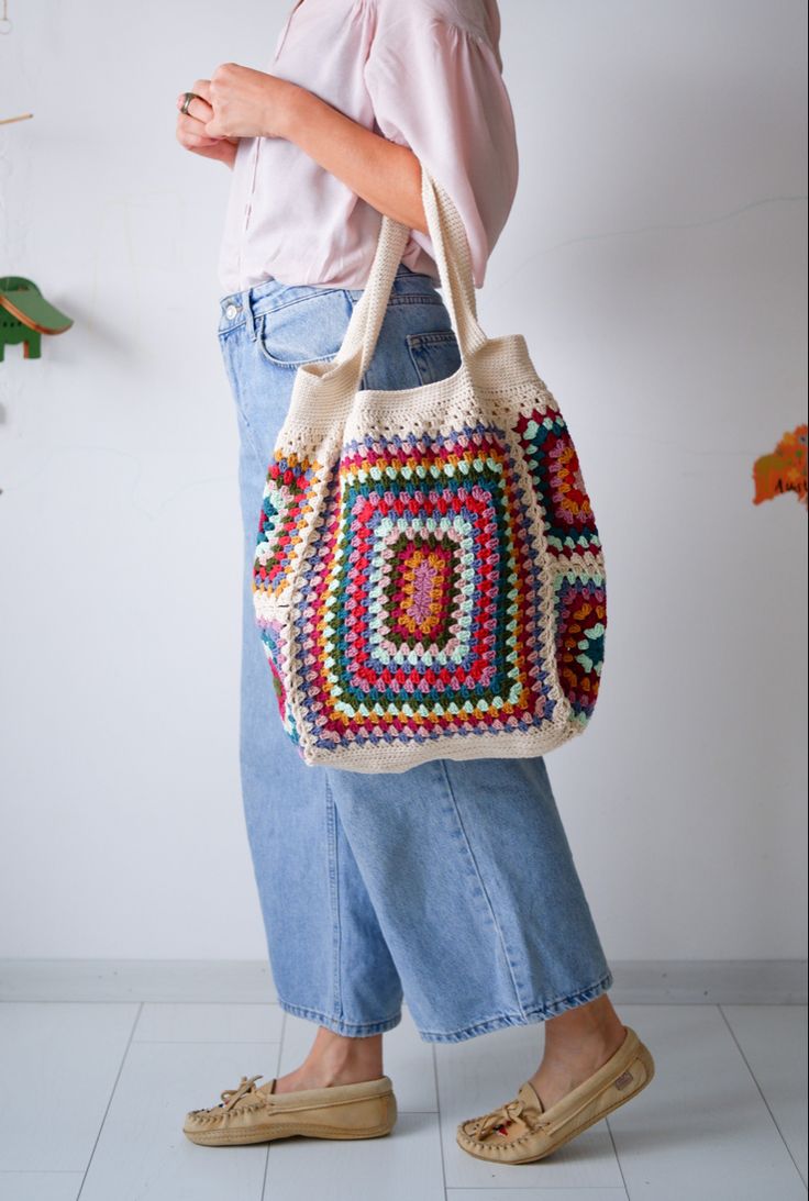 a woman holding a crocheted bag in her hands