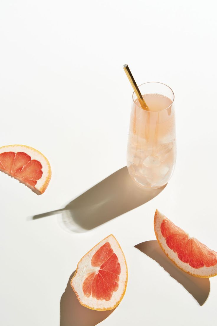 grapefruit slices are cut in half and placed next to a glass with a straw