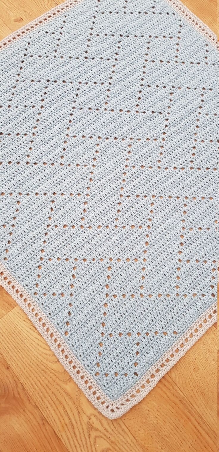 a blue crocheted rug on the floor with wood floors in the background and a wooden floor