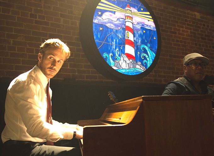 a man sitting at a podium in front of a stained glass window with a lighthouse on it