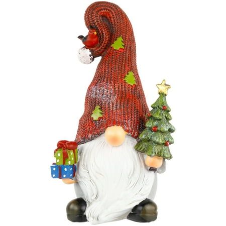 a santa clause figurine with presents on his feet and holding a christmas tree