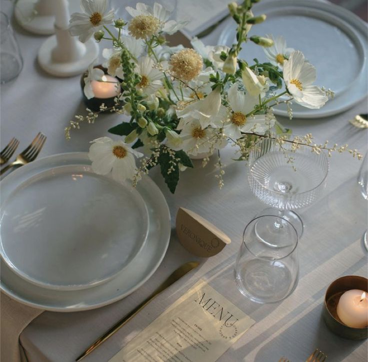 a table set with plates, silverware and flowers