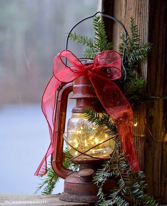 an old fashioned lantern with christmas lights in it and a red bow on the handle