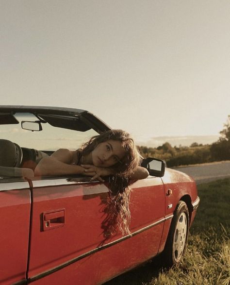 a woman laying down in the back of a red car