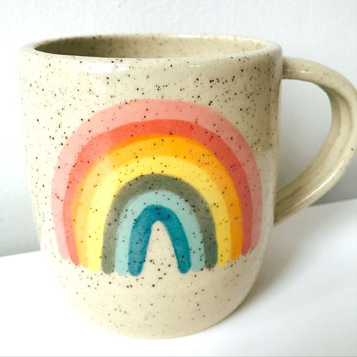 a coffee cup with a rainbow painted on it