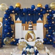 a blue and gold birthday party with balloons, table settings and decorations on the walls