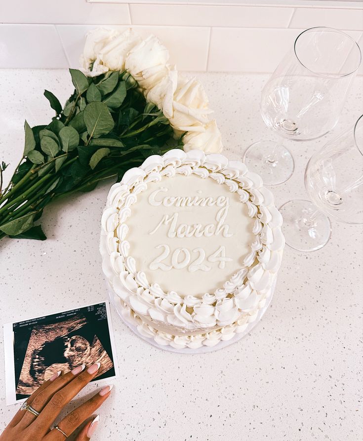 a white cake sitting on top of a table next to wine glasses