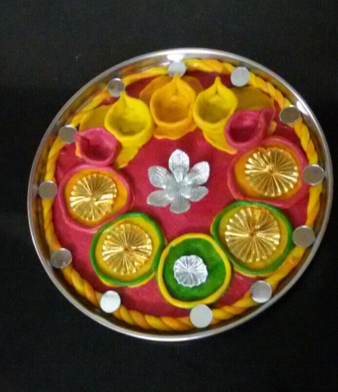 a decorative plate with gold, red and green decorations on black tableclothed surface