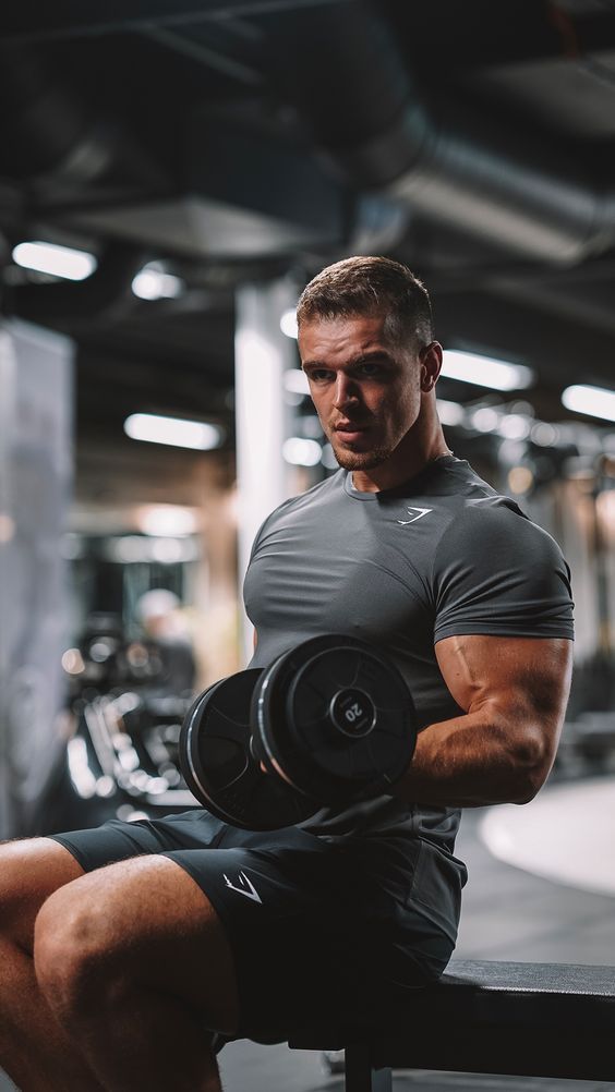 a man sitting on top of a bench holding a pair of dumbbells