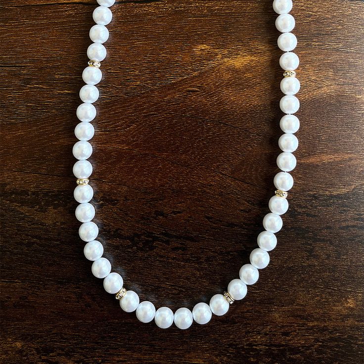 In a world saturated with mediocrity, nothing can rival the authenticity of traditional luxury. This subtly opulent necklace showcases genuine white freshwater pearls, elegantly interspersed with lab diamond studded rondelles in gold. Hand-strung with care in our Orlando studio, this gorgeous necklace is secured with a gold bonded lobster clasp. Our Men's Pearls Collection, features sophisticated fresh water pearl necklaces and bracelets, designed especially for men. Drawing inspiration from his Timeless Pearl White Round Bead Jewelry, Timeless Pearl White Round Beaded Jewelry, Timeless White Pearl Chain Necklace, Formal White Round Bead Necklaces, Classic Everyday Necklaces With Round Beads, White Classic Jewelry For Everyday, Elegant White Round Beaded Necklaces, Everyday White Single Strand Necklace, Classic White Everyday Jewelry