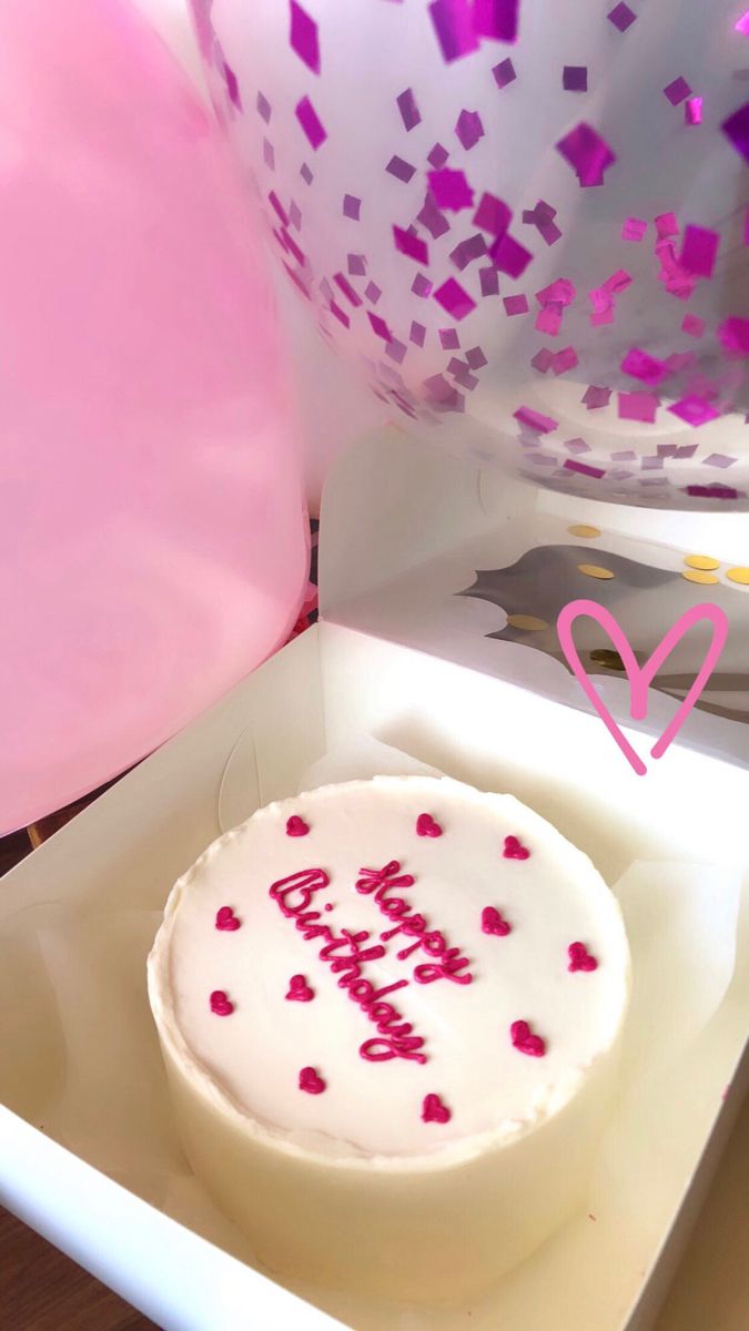 a birthday cake with pink and purple confetti on it sitting in a box