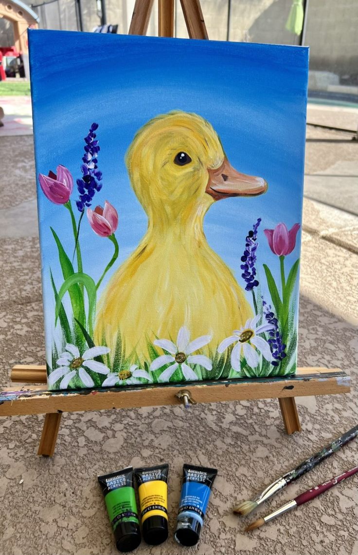 an easel with paint and watercolors sitting on the ground next to it