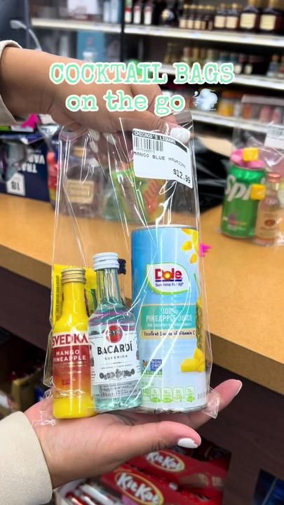 a person holding up a plastic bag filled with sodas and juice bottles in a store