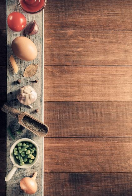 an overhead view of various vegetables on a wooden table with spoons and seasonings