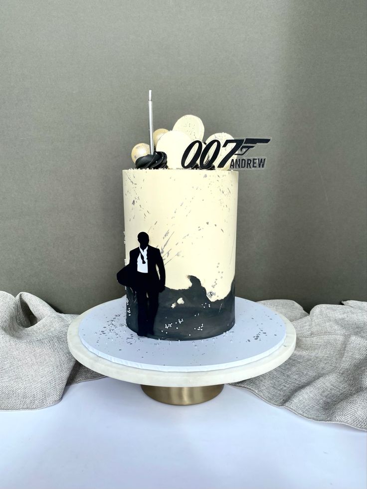 a white and black wedding cake sitting on top of a table next to a gray wall