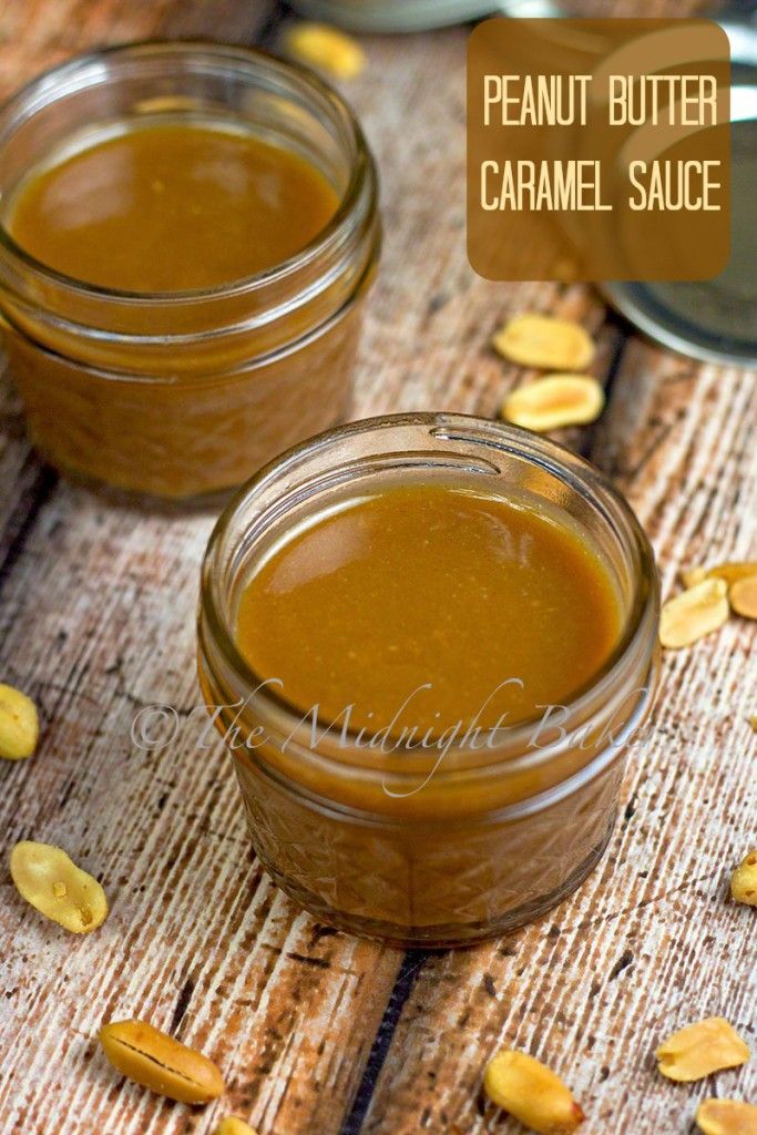 two jars filled with peanut butter sitting on top of a wooden table next to spoons