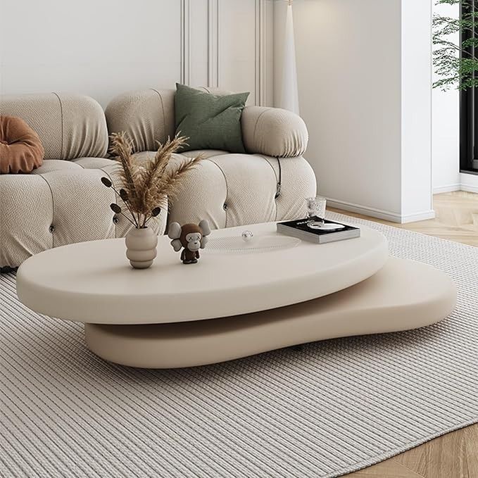 a living room with a couch, coffee table and plant on the floor in front of it