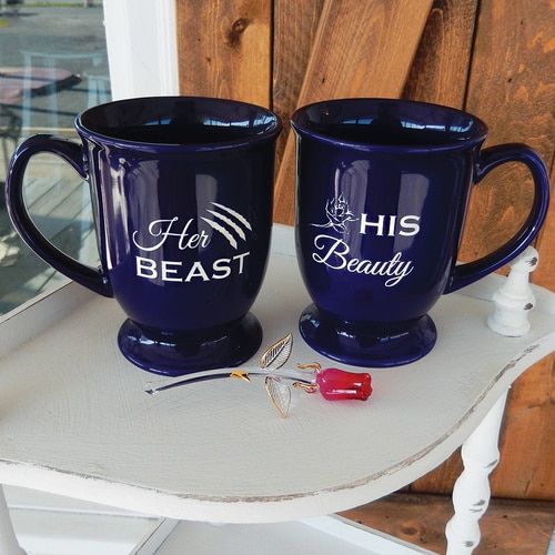 two blue coffee mugs sitting on top of a white table next to each other