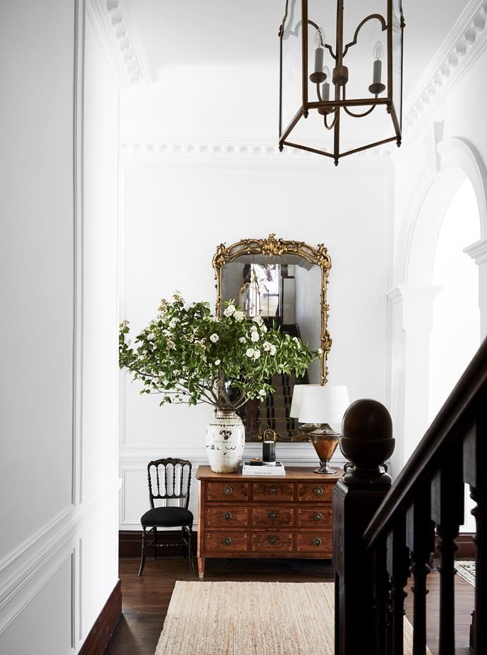 a room with a dresser, mirror and plant on the table in it's centerpiece