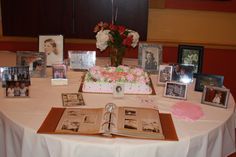 a table topped with pictures and flowers on top of a white cloth covered tablecloth