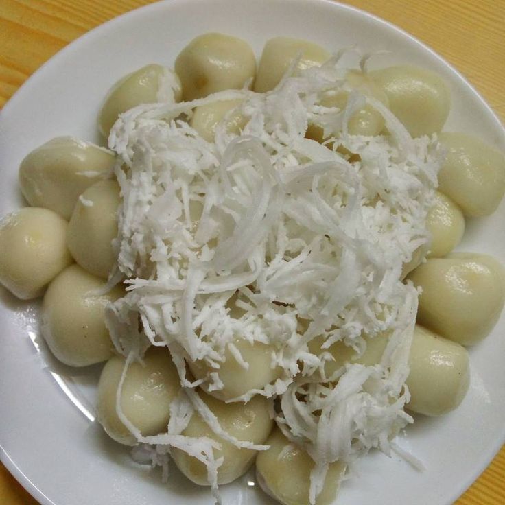 a white plate topped with ravioli covered in grated parmesan cheese on top of a wooden table