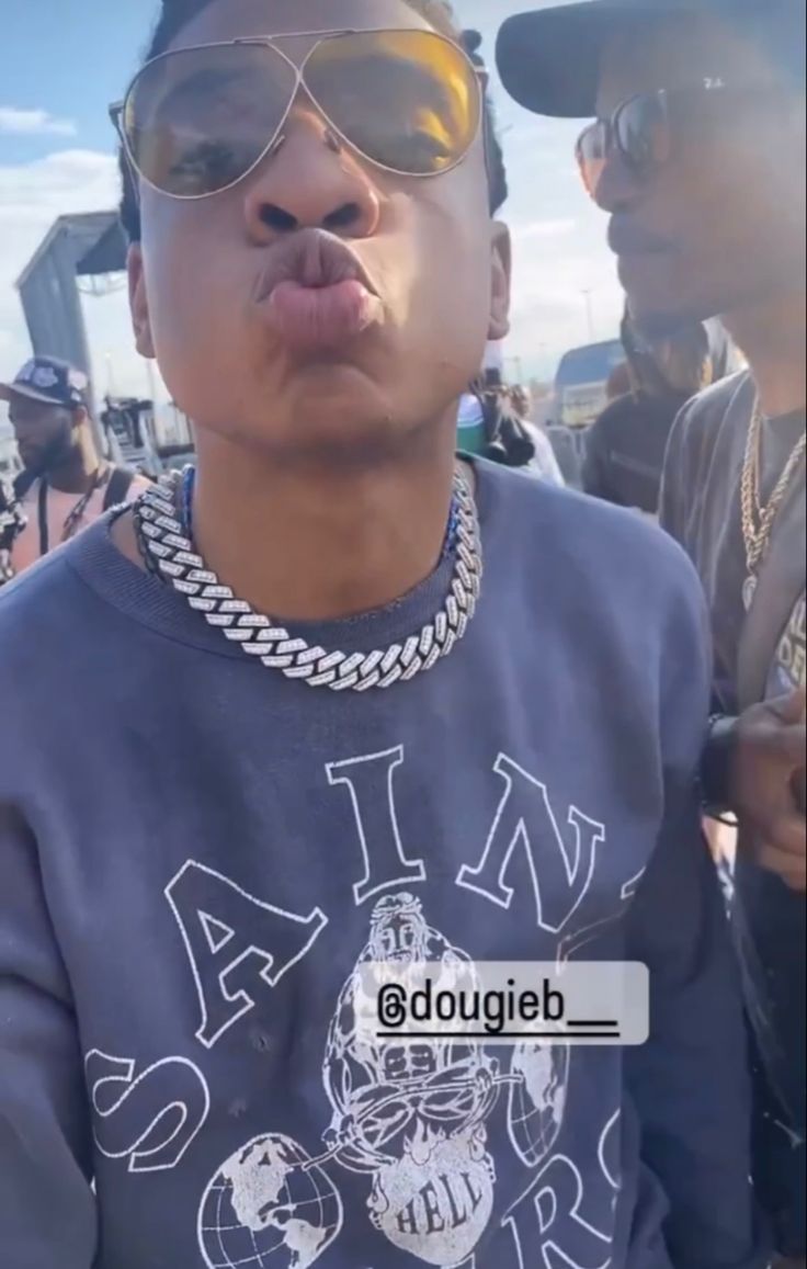 a young man wearing sunglasses making a funny face while standing in front of other people