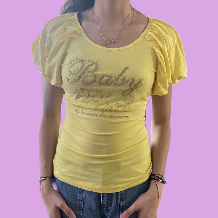 Vintage Baby Phat With Ruffled Sleeves. It Is A Standard Yellow Color With A Bejeweled Touch. The Shirt Itself Has A Small Stain Near The Bottom (Probably Makeup Smudge), However It Is New Without Tags, And I Have Never Worn It Before- So I Didn't Want To Wash It And Possibly Ruin The Jewels. Great Condition! Y2k Stretch Tops With Rhinestones, Y2k Party Tops With Rhinestones, Y2k Summer Tops With Rhinestones, Summer Y2k Tops With Rhinestones, Makeup Smudge, Baby Phat, Ruffled Sleeves, Vintage Baby, Yellow Color