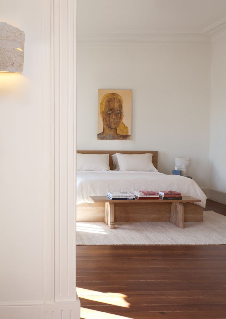 a bed sitting in a bedroom next to a wooden table on top of a hard wood floor