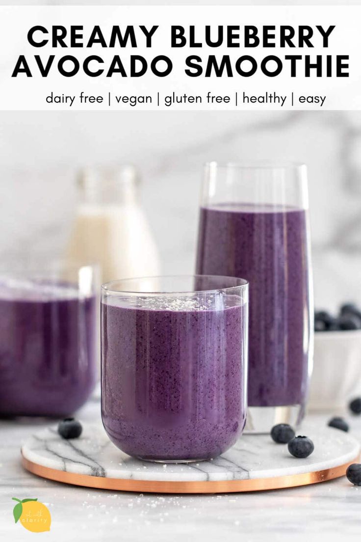 two glasses filled with blueberry avocado smoothie on top of a marble plate