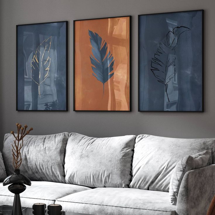 three paintings hang on the wall above a couch