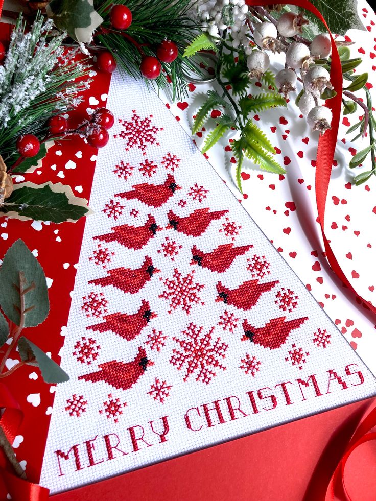 a cross stitch christmas card with red and white decorations