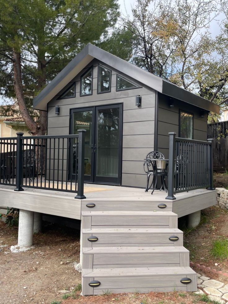 a small house with stairs leading up to the front door and decking on top of it