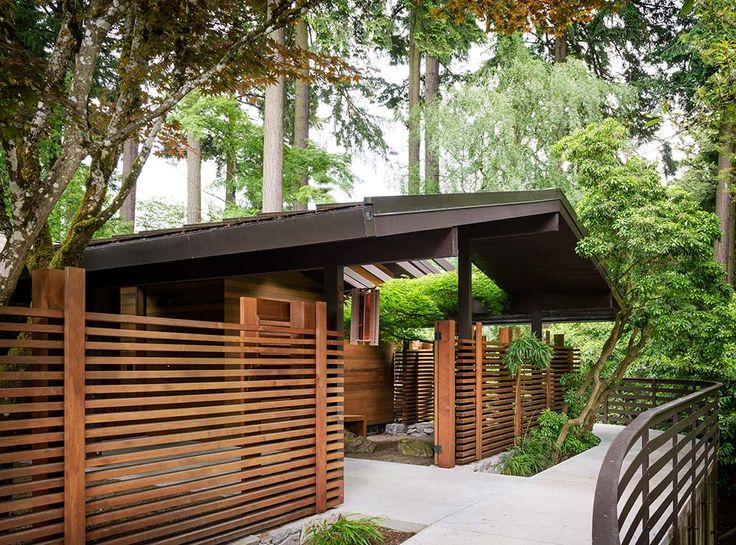 an outdoor area with wooden fences and trees in the background, along with a walkway leading up to a covered pavilion