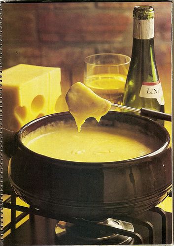 there is a bowl of soup on the table next to some cheese and wine bottles